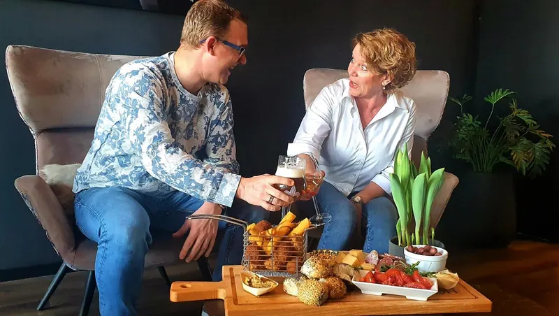 Wooden board with bread rolls, cheese, smoked fish and warm bites on a table at BØFF