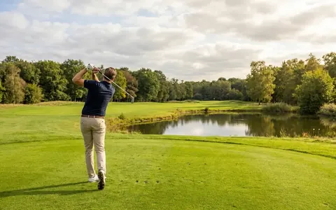Golfer slaat af op een fairway langs het water