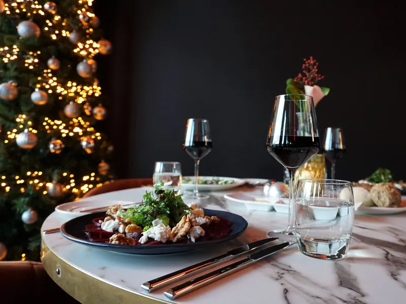Gedekte tafel met een gerecht en wijnglazen naast de kerstboom