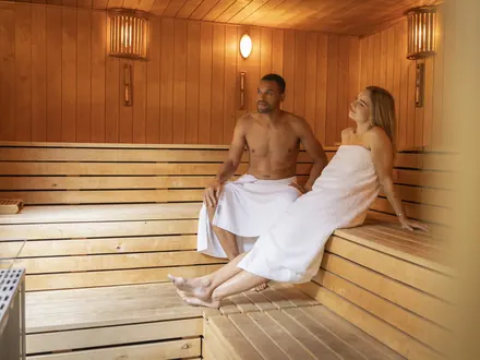 Paar in Handtüchern auf der Bank der Sauna
