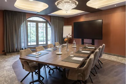 Tagungsraum in Boardroom-Bestuhlung mit großem Bildschirm und Flipchart