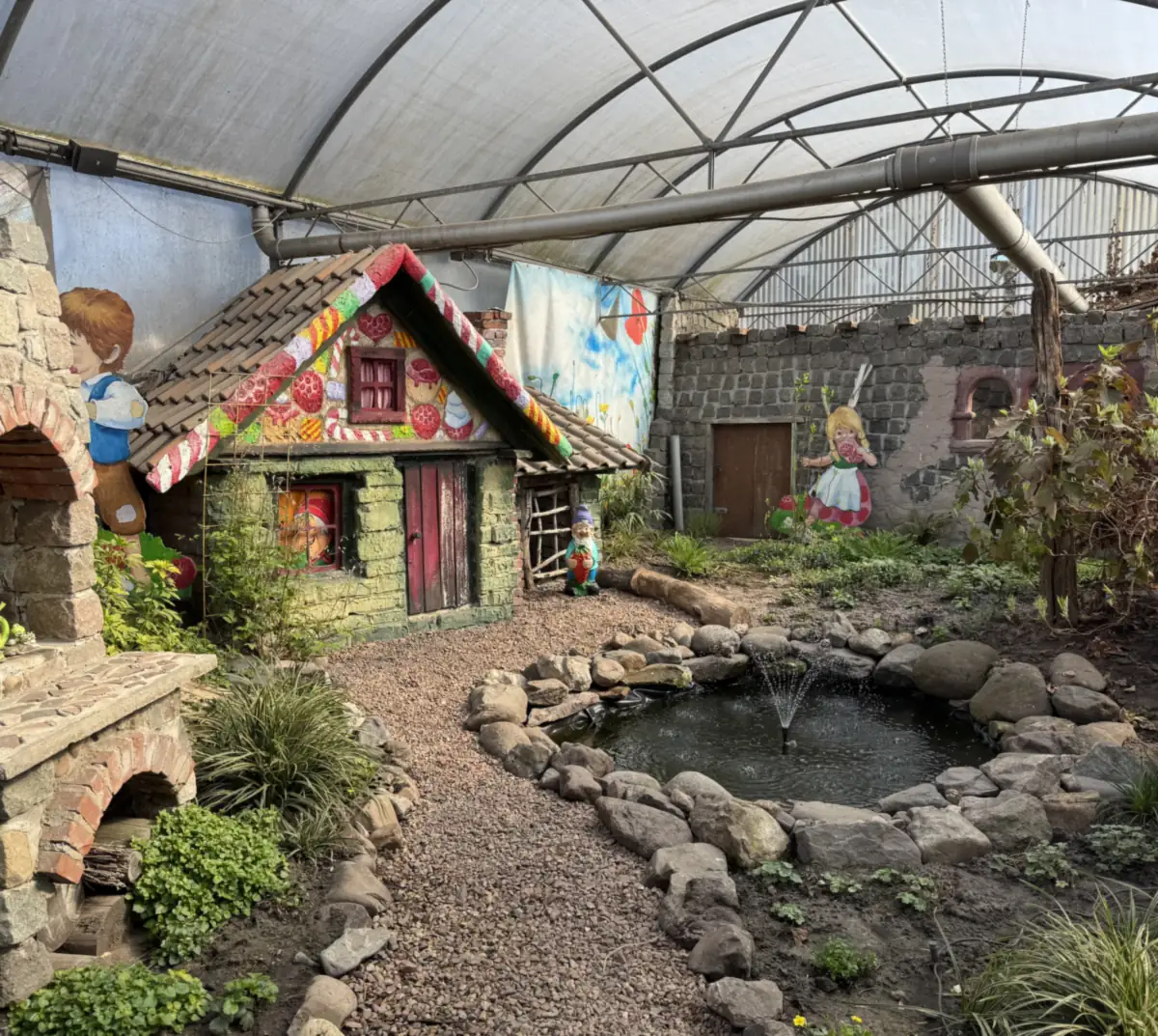 Sprookjeshuisje met aardbeien op het dak en een vijvertje in de voormalige aardbeienkas van Het Aardbeienland