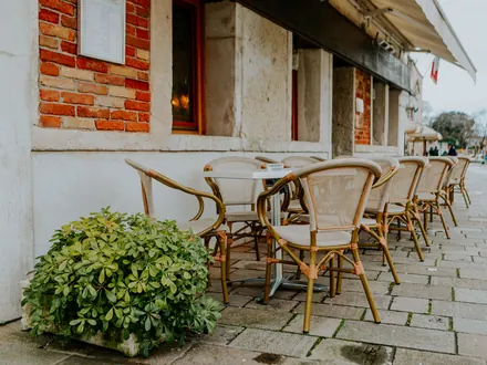 Leeg terras met rieten stoelen en tafeltjes langs een gevel