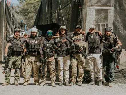 Gruppe von Airsoft-Spielern in taktischer Ausrüstung nebeneinander auf dem Feld