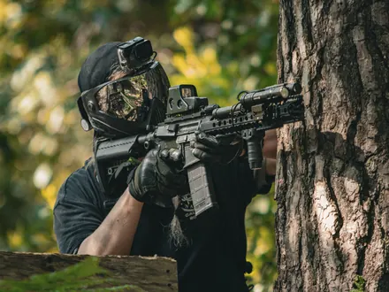 Spieler mit Gesichtsmaske, Brille und Replik hinter einem Baum