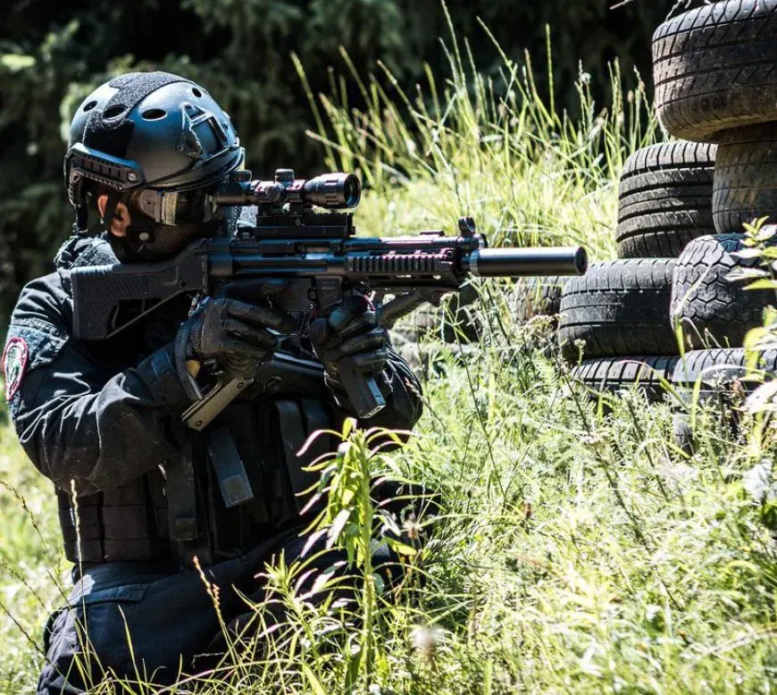 Spieler von Airsoft Brothers zwischen Reifen und hohem Gras