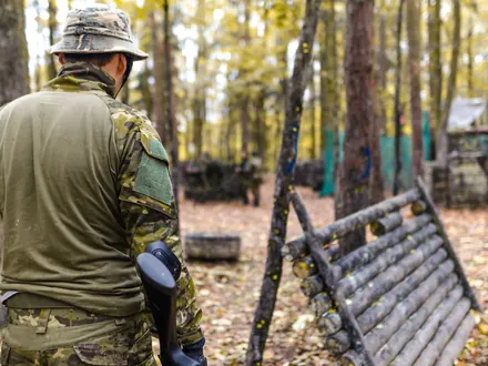Spieler in Tarnkleidung auf einem Waldfeld mit Holzbarrikaden