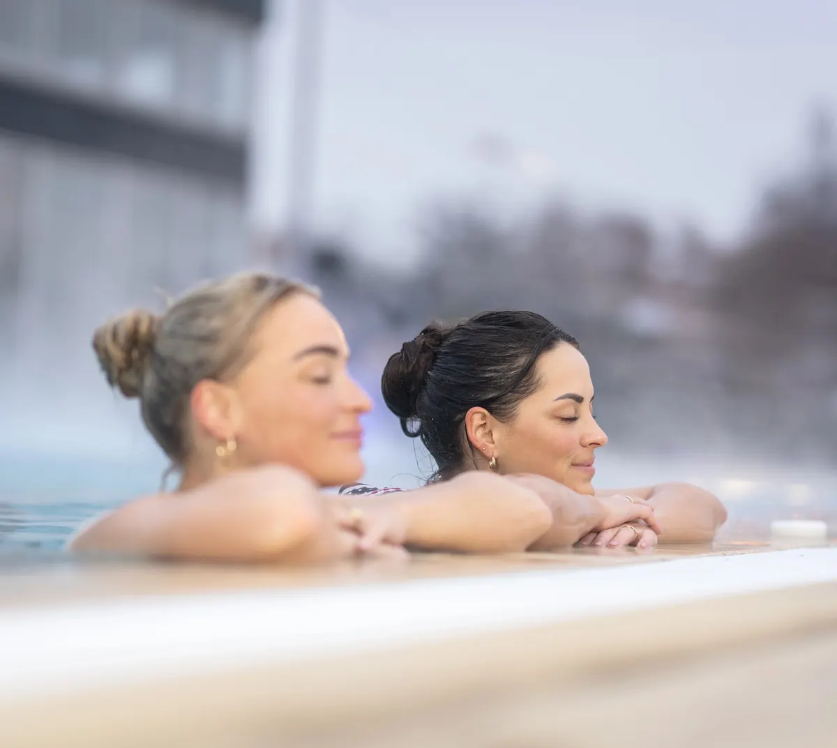 Zwei Gäste im warmen Außenbecken des Thermalbad Arcen, mit Dampf über dem Wasser