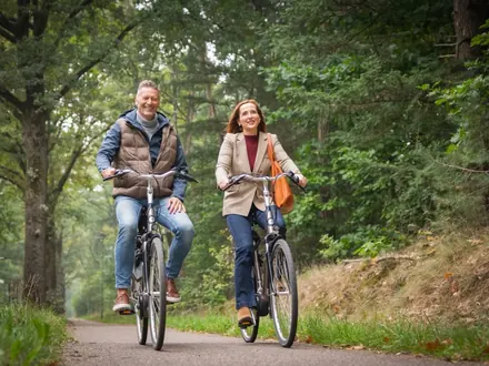 Man and woman cycling along a woodland path