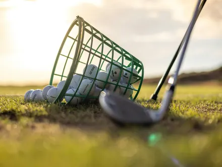 Basket of golf balls and a golf club on the grass of a practice ground