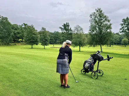 Golferin mit Trolley auf dem Fairway, bereit für ihren Schlag