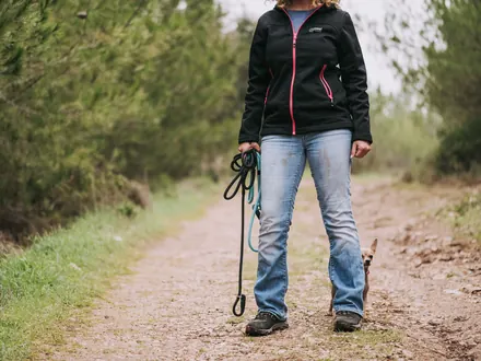 Wanderer mit Hund an der Leine und festen Schuhen auf einem Sandweg