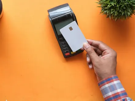 Hand houdt een bankpas bij een pinautomaat