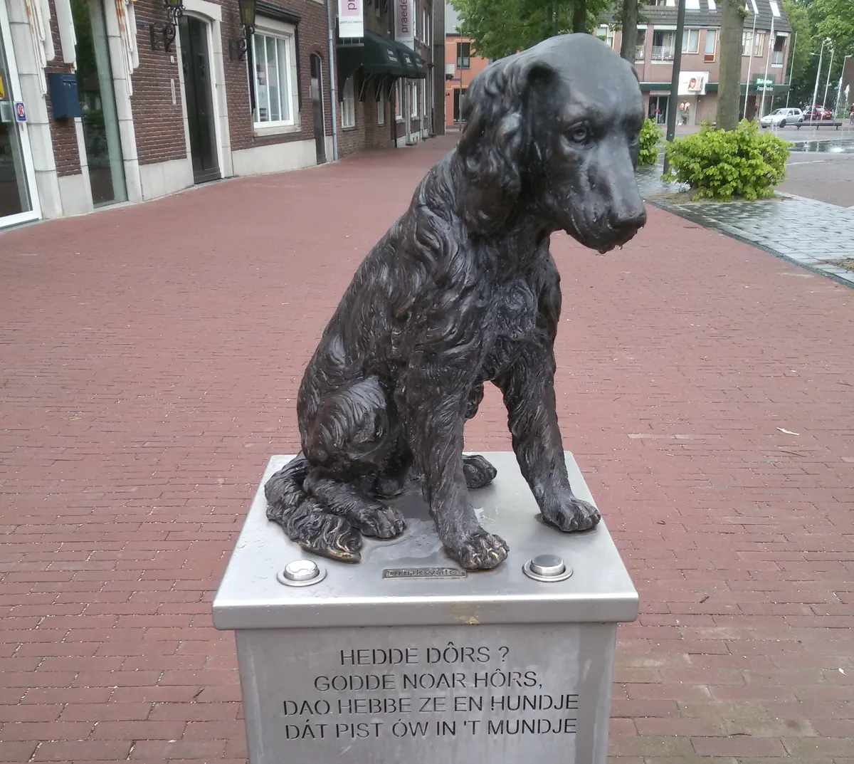 Das bronzene Horster Hundje mit dem Vers Hedde dôrs, Godde naor Hôrs auf dem Sint Lambertusplein in Horst