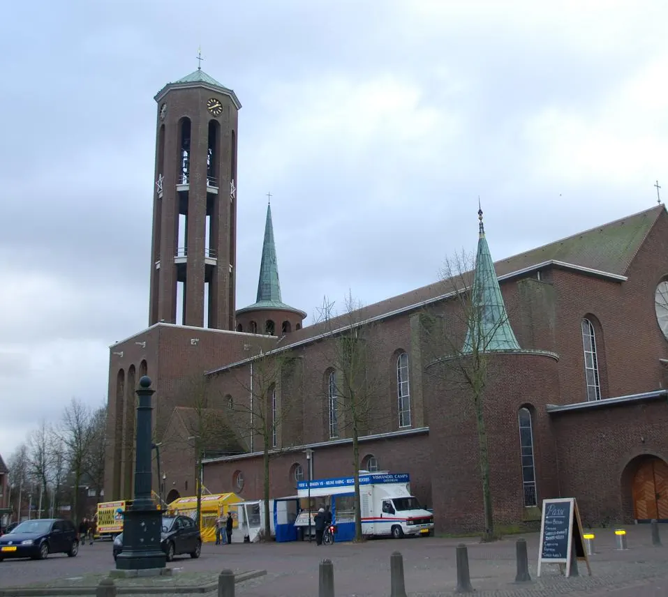 Die Sint-Lambertuskerk mit ihrem offenen Glockenturm am Sint Lambertusplein in Horst, mit Marktwagen vor der Kirche