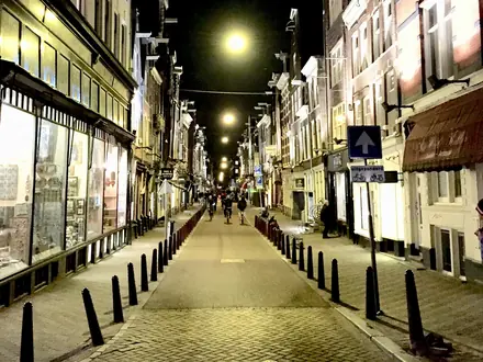 Einkaufsstraße am Abend mit beleuchteten Schaufenstern und Straßenlaternen