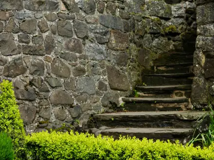 Unebene Steinstufen an einer alten Natursteinmauer