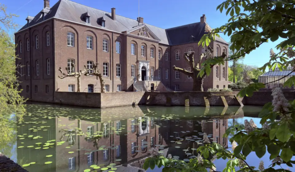 Schloss Arcen spiegelt sich im Graben mit Seerosen, im Frühling