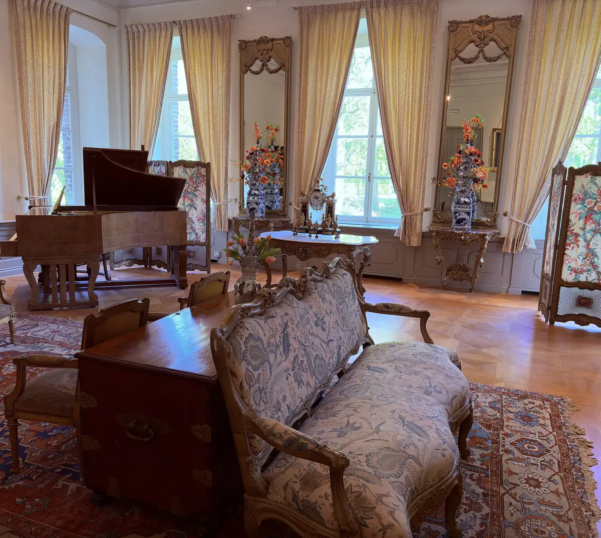 Salon in der Beletage von Schloss Arcen, mit Flügel, antikem Sofa und Blumengestecken