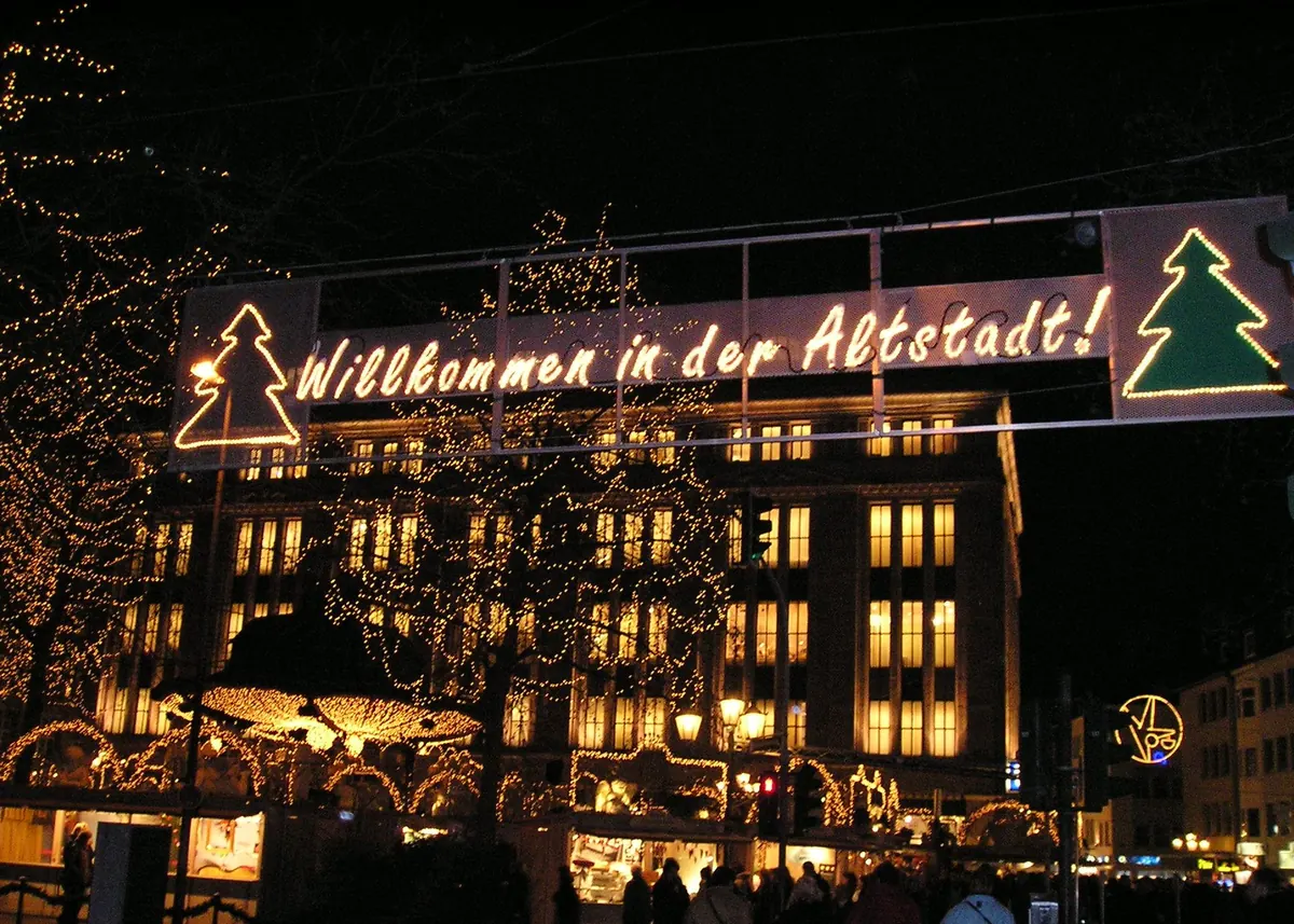 Beleuchteter Weihnachtsmarkt in der Düsseldorfer Altstadt, unter dem Leuchtschild Willkommen in der Altstadt