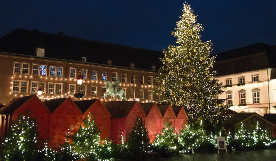 Beleuchteter Weihnachtsbaum, Weihnachtsmarktbuden und das Reiterstandbild auf dem Marktplatz in Düsseldorf am Abend