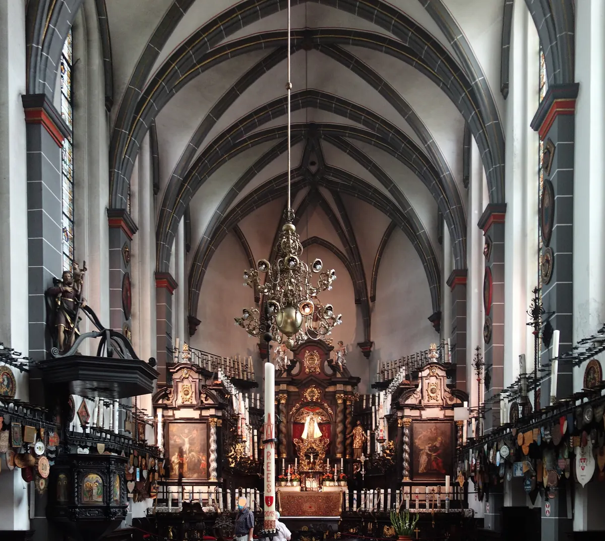 Das Innere der Kerzenkapelle in Kevelaer, mit Kronleuchter, barockem Altar und Pilgerschilden an den Wänden