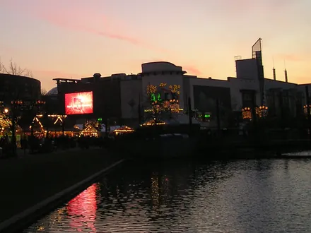 Weihnachtsmarkt am Einkaufszentrum in Oberhausen in der Abenddämmerung, mit Lichtern, die sich im Wasser spiegeln