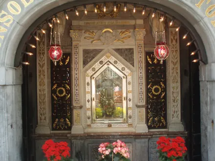 Het genadebeeld in de Gnadenkapelle, met lampen en rode bloemen