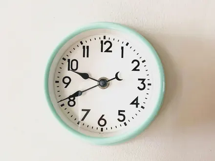 Wanduhr mit mintgrünem Rand an einer hellen Wand