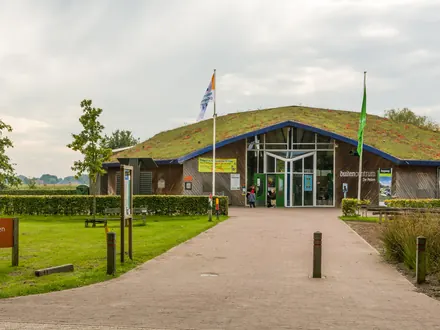 Besucherzentrum De Pelen in Ospel, ein flaches Gebäude mit Grasdach am Ende eines Weges