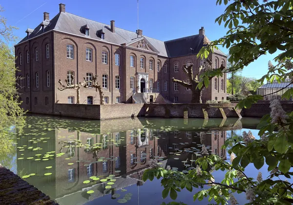 Schloss Arcen spiegelt sich im Graben mit Seerosen