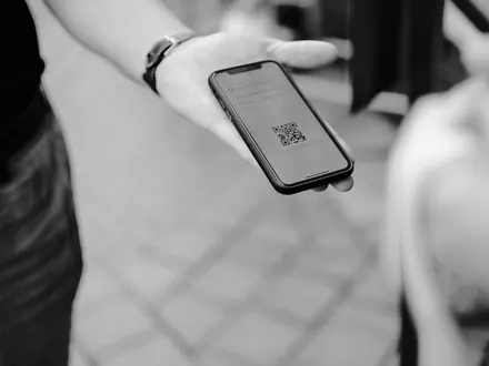 Hand mit einem Handy, auf dem ein E-Ticket mit QR-Code zu sehen ist