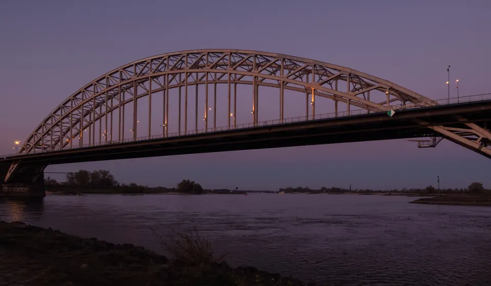 Die Waalbrücke in Nijmegen in der Dämmerung, mit dem beleuchteten Bogen über der Waal