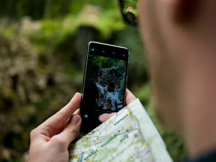 Walker with a walking map and a phone showing the route