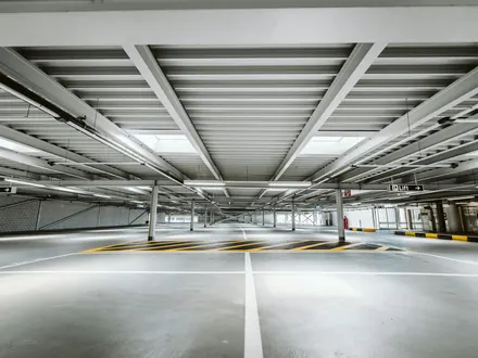 Helles, leeres Parkhaus mit Betonbalken und Stellplätzen