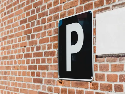 Parkeerbord met een witte P op een bakstenen muur