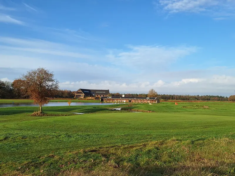Clubhaus des Golfplatzes De Swinkelsche am Wasser, mit dem Platz im Vordergrund
