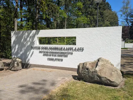Weiße Eingangsmauer des deutschen Soldatenfriedhofs Ysselsteyn mit Findlingen davor
