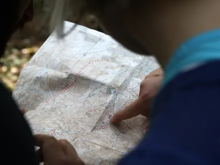 Zwei Wanderer zeigen auf einer Papierkarte eine Route
