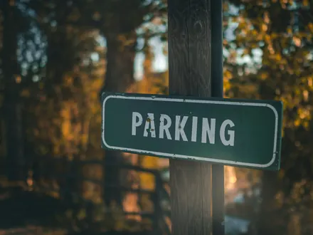 Green parking sign on a wooden post among the trees