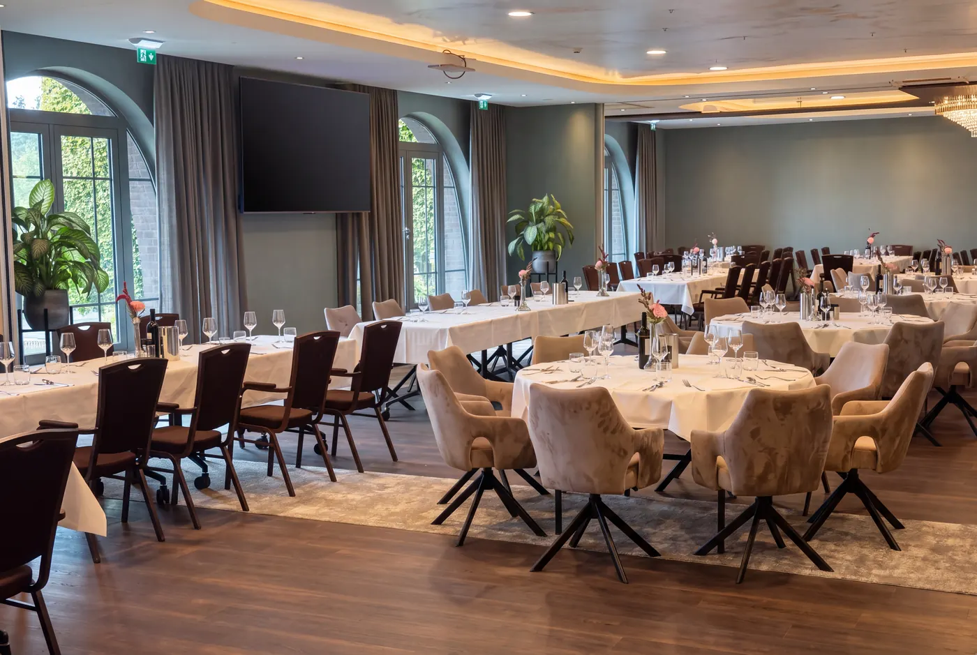 Function room with arched windows, round tables and velvet chairs