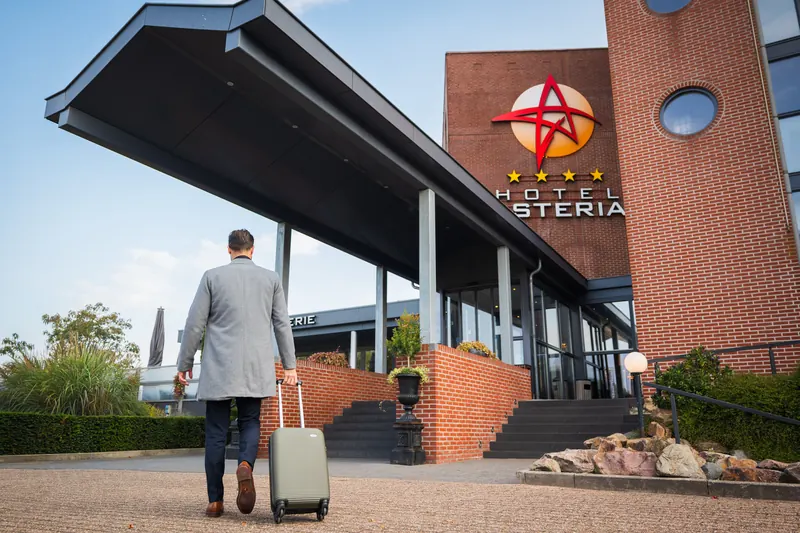 Een gast met koffer loopt naar de ingang van Hotel Asteria in Venray