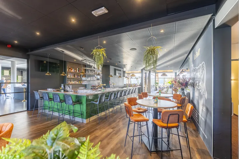 De groene bar van BØFF met barstoelen en hangende planten
