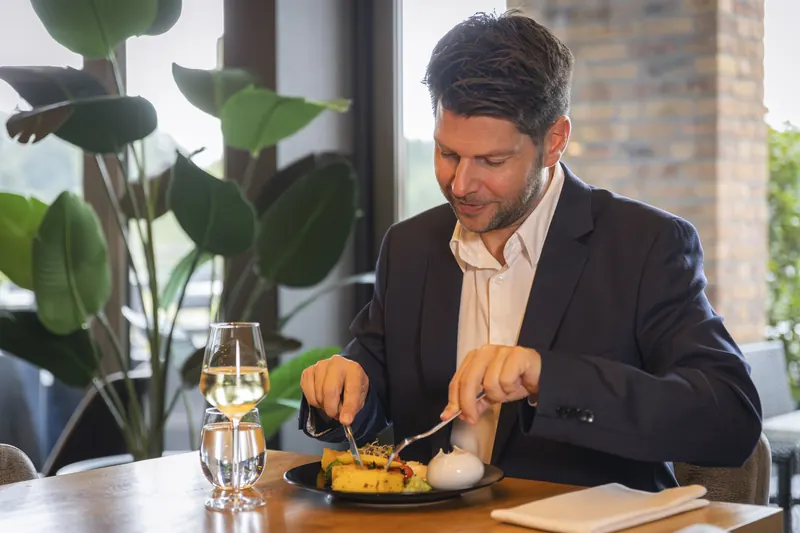 Zakelijke gast aan tafel in restaurant BØFF met een glas witte wijn