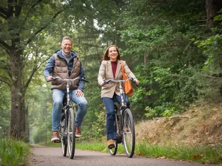 Stel fietst over een bospad bij Horst