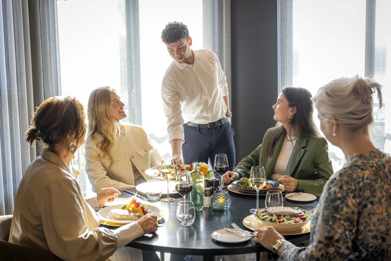 The waiter serves lunch to four guests in the BØFF brasserie