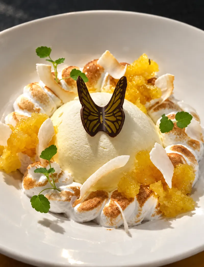 Pineapple and meringue from restaurant BØFF: pineapple parfait with meringue, pineapple compote and toasted coconut on a white plate
