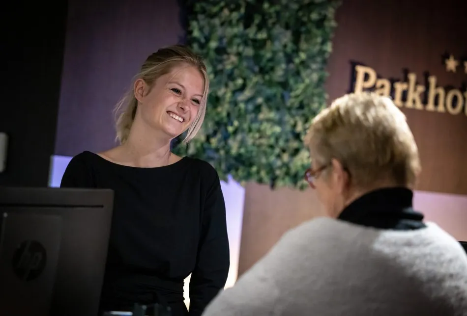Receptiemedewerker verwelkomt een gast aan de balie van Parkhotel Horst